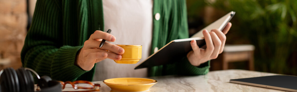 Young man enjoying coffee while jotting notes in a modern cafe setting
