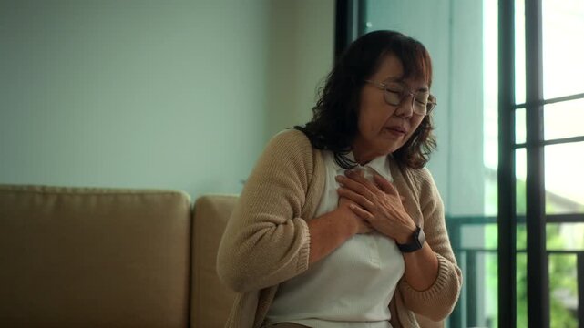 Unhealthy elderly woman having chest pain and difficulty breathing alone at home, heart attack symptoms and cardiac emergency in retirement age, urgent medical care needs and health life insurance.
