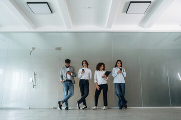 Fototapeta premium By the wall. Front view of four office workers that are standing indoors and waiting