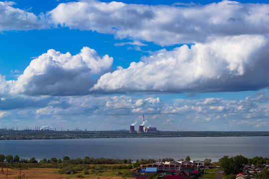Power plant by lake under bright beautiful clouds