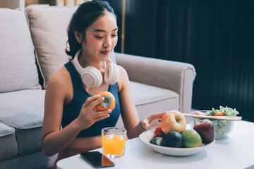 Fit young Asian women in activewear sitting on yoga mat and eating fresh vegetable salad after workout, representing clean eating, fitness lifestyle, wellness routine and health balance.