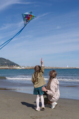 Mother and daughter flying a kite at the beach