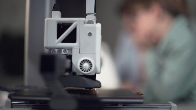 3D printer in operation in the foreground with kids on background
