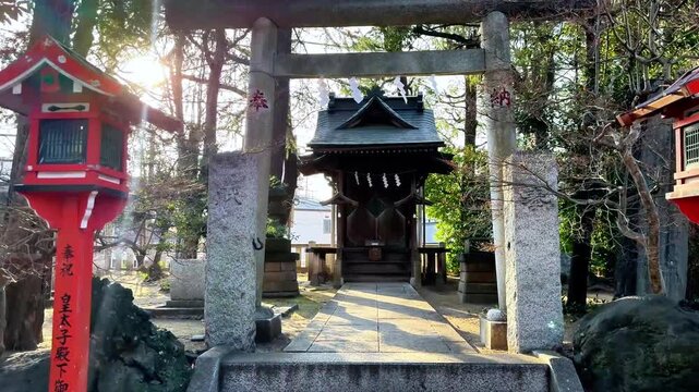 Stone torii gate leading toward a wooded Japanese shrine