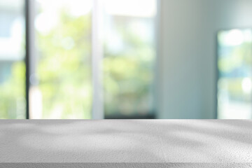 Fototapeta premium abstract blurred garden view form living room window with modern plain concrete table counter background for show , promote ,design banner ads on display concept