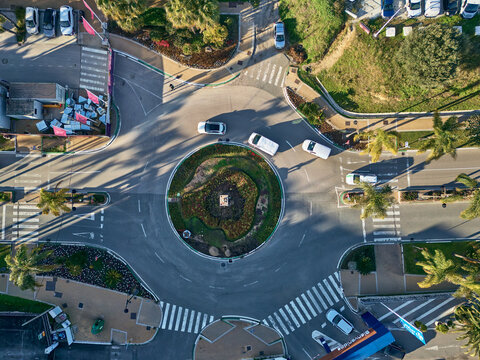 Estepona, Spain - 19 January 2026: Aerial view of a roundabout, where zebra crossings lead to and from the circle, creating a dynamic interplay of light and shadow on asphalt.