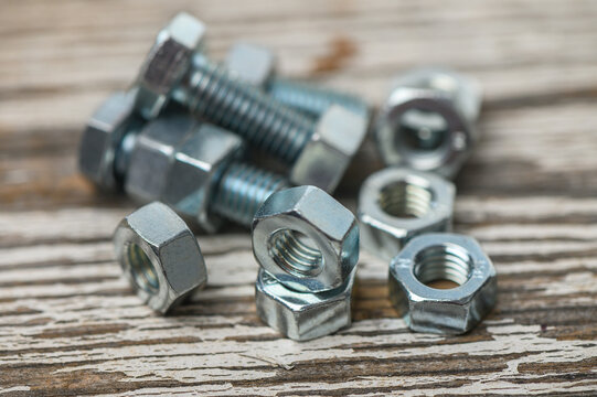 Close-up of M8 nuts and bolts on rustic wooden surface