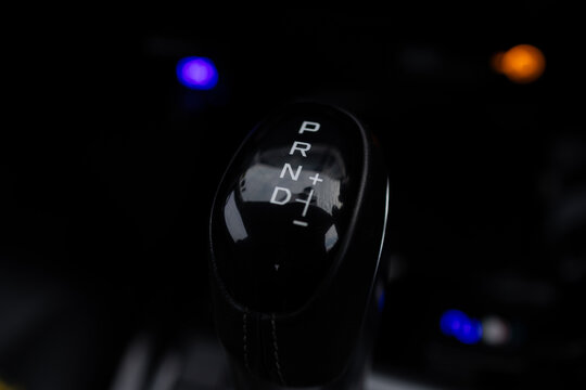 Close-up of Modern Automatic Gear Shifter with Manual Mode,A high-angle, close-up shot of a sleek black automatic transmission gear lever in a car interior, showing the P, R, N, D positions.