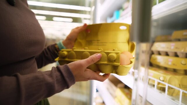 Woman Opens A Freezer Door And Takes A Pack Of Eggs In The Supermarket's Product Section While Shopping