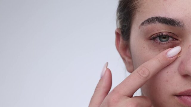 4K slow motion closeup of young woman applying concealer under eye with finger in one smooth stroke