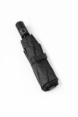 Folded black automatic umbrella isolated on white background