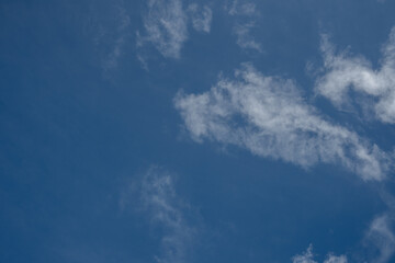 Isolated thin white cloud patches against a deep blue sky