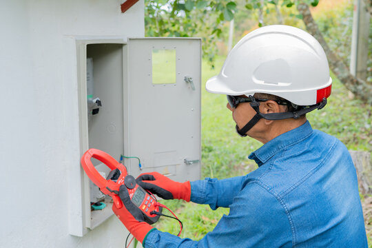 Professional electrician using a clamp meter to measure the flow of electric current