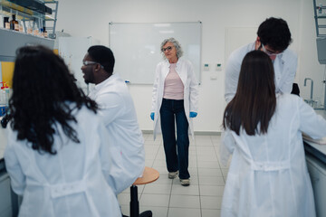 Experienced professor teaching diverse students in science laboratory