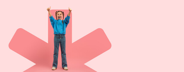 A girl stands in a playful pose, raising her arms with excitement. She wears casual clothing and...