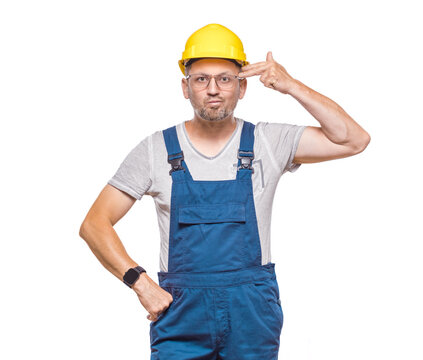 One construction worker makes finger gun gesture in temple, pretends committing suicide, isolated on white background. Craftsman against white wall
