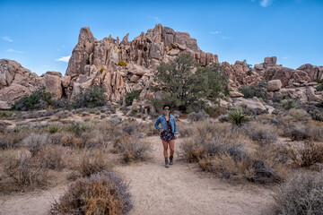 Obraz premium A woman stands in a desert with a blue jacket and a hat