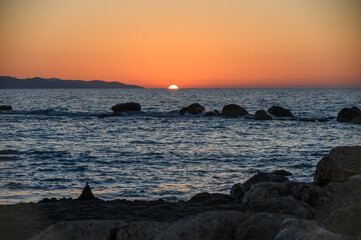 Fototapeta premium Beautiful summer sunset in Cyprus with mountains and Mediterranean Sea. Warm golden light over calm water creates tranquil and romantic holiday scenery