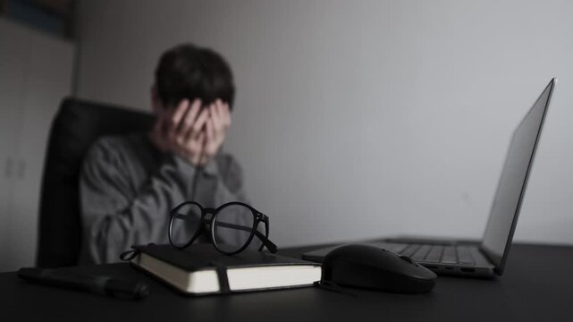 Unexpected project failure reaction, man at desk in home office covering face with hands, coping with work setback and stress.