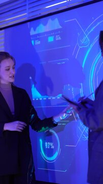 Corporate team collaborating on digital transformation strategy. Business professionals analyzing performance metrics on smart interactive display during night shift.