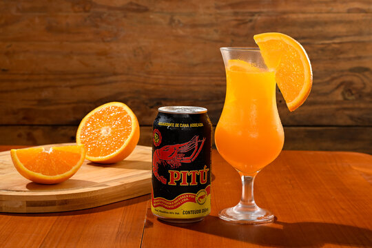 S&atilde;o Paulo, SP, Brazil - February 2026: Can of Pitu (a type of Brazilian rum) with orange drink on a wooden table.