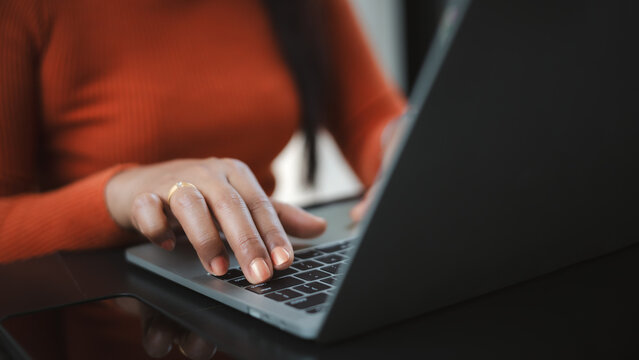 Close up of a woman's hands with orange nails typing on a laptop keyboard. Concept of remote work, professional freelancer, online business communication, and modern digital lifestyle.