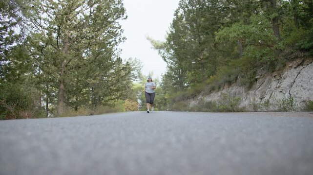 Overweight Woman Exercising Outdoors by Running in Mountains at Sunset to Burn Fat and Stay Healthy