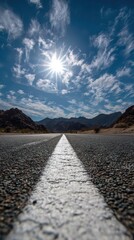Low Angle View of a Highway with White Line Leading Towards Distant Mountains Under a Sunny Bright Blue Sky with Scattered Clouds