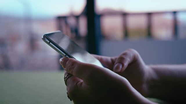 Close-Up Shot of Woman Using Mobile Phone on Veranda with Scenic Mountain Landscape