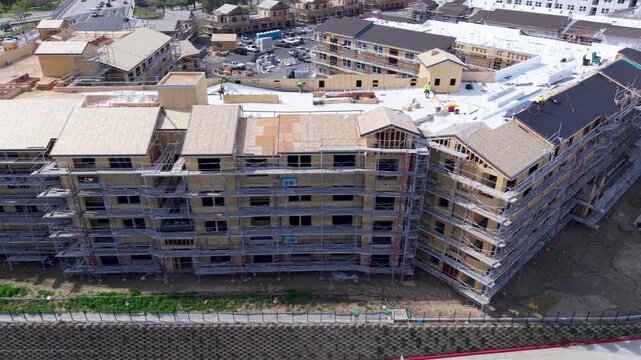 Workers are constructing a residential building using scaffolding and implementing earthquake resistant techniques at the site.