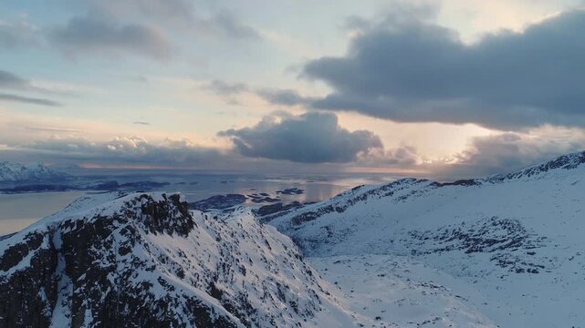Snowy mountain landscape with ocean view at sunset