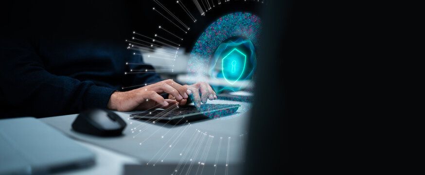 Professional software engineer working on cybersecurity with shield hologram and AI assistant on computer screen. Concept of data protection, network security, and digital innovation.