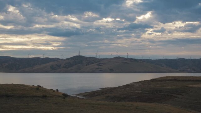 Calm Los Vaqueros Reservoir at sunset with a distant wind farm