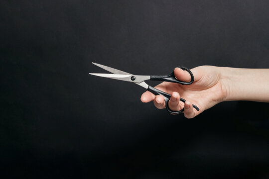 Hand Holding Tailor Scissors on black Background