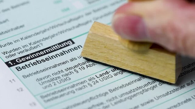 Ein Formular zur Einkommensteuer wird vom Finanzamt mit einem Stempel markiert - FOTOMONTAGE