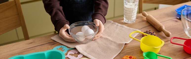 Joyful little boy preparing for a fun baking adventure with eggs and vibrant tools in the kitchen © Bliss