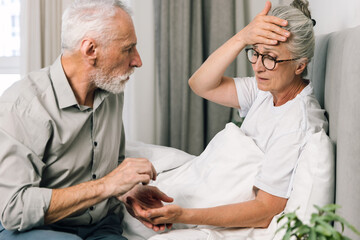 Obraz premium Senior man gives pill to sick wife in bedroom