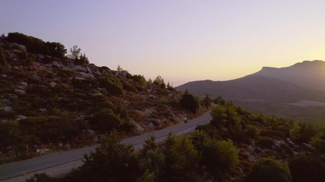 Obese Woman Jogging on Road Surrounded by Stunning Sunset Mountain Landscape for Slimming, drone view