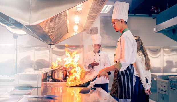 Senior male chef teaches young teenage boys cooking in school kitchen. Education Concept