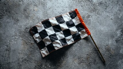 Naklejka premium Checkered flag sits on a gray surface, seen from above. Room for words.
