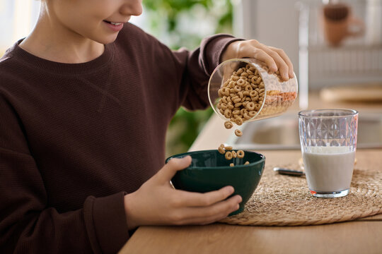 Little boy enjoys a joyful breakfast moment pouring cereal into a bowl