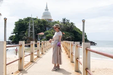 Fotobehang Lotusbloem Woman tourist holding lotus flowers on her way to Parevi Duwa temple in Matara, Sri Lanka. Close-up of Buddhist offering at the island bridge over Indian Ocean.  © Сергей Дудиков