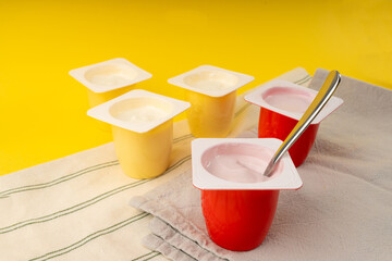 Yogurt cups set, pink and yellow fruit yoghurt in plastic pots, milk pudding container with spoon