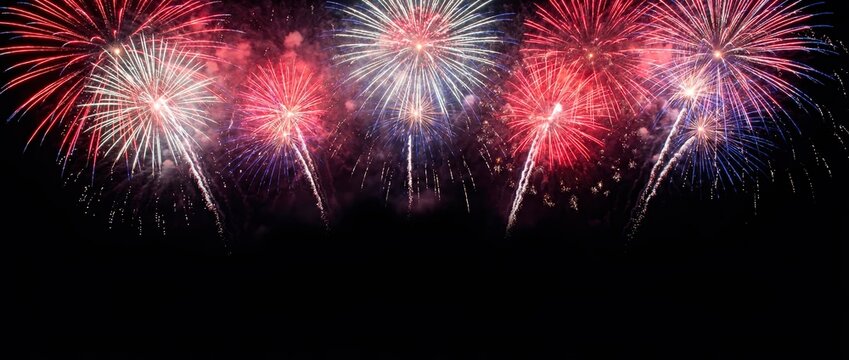 Colorful fireworks display against a black night sky. Red white and blue pyrotechnics for celebration. Independence Day background