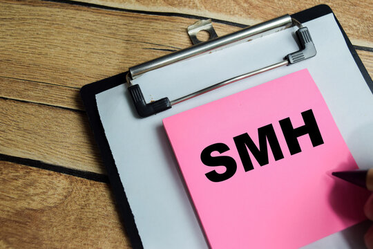 Concept of SMH - Shaking My head write on sticky notes isolated on Wooden Table. For popular social media to express disappointment or disbelief
