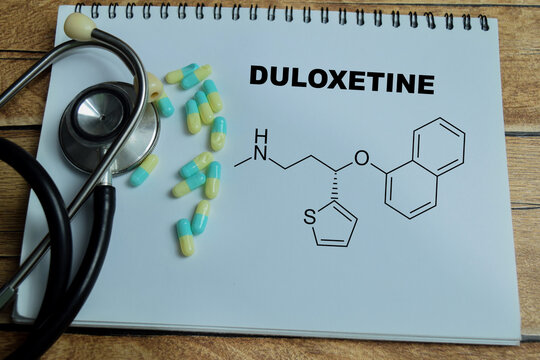 Concept of duloxetine antidepressant medication write on book isolated on Wooden Table. SNRI treatment for depression anxiety and chronic pain management in mental healthcare