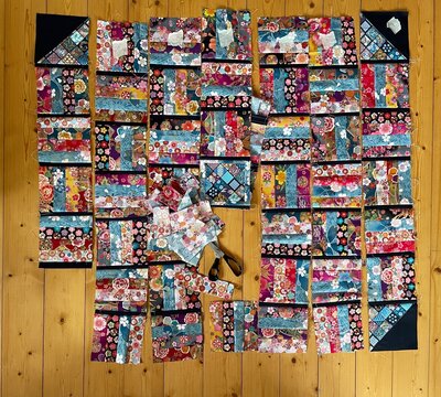 A colorful patchwork and quilt made of Japanese cotton fabrics is designed and assembled on a wooden floor