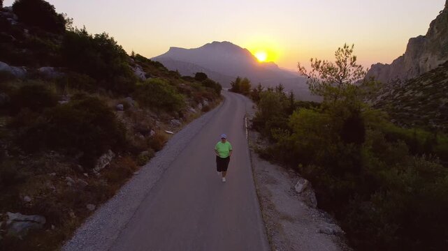 Overweight Woman Running on Asphalt Road Surrounded by Scenic Views at Sunset for Fitness, drone view