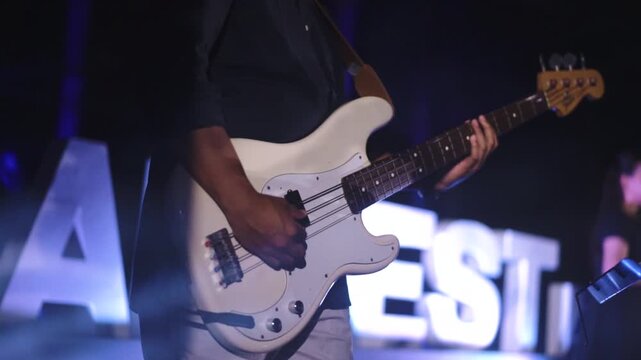 Close-up of bassist playing electric bass guitar while performance