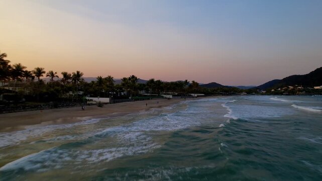 Aerial Drone View of Tropical Beach at Sunset with Palm Trees and Orange Sky